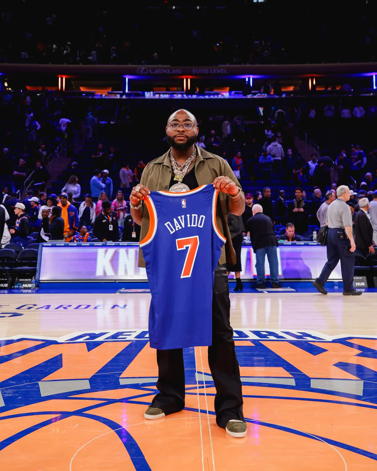 Davido at center court in Madison Square Garden holding a Knicks jersey with his name and the number 7